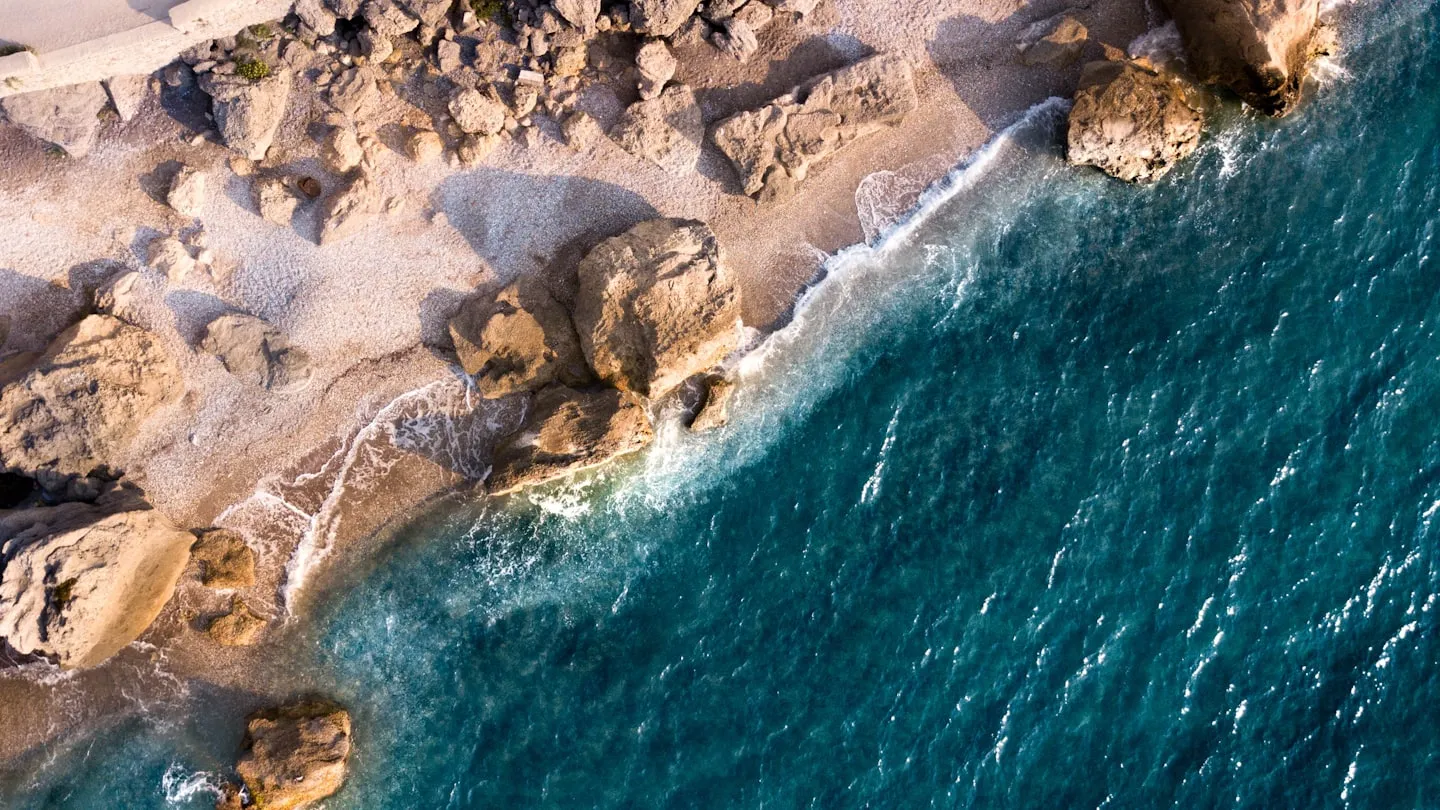 Aerial view of deep blue water along a rocky shoreline